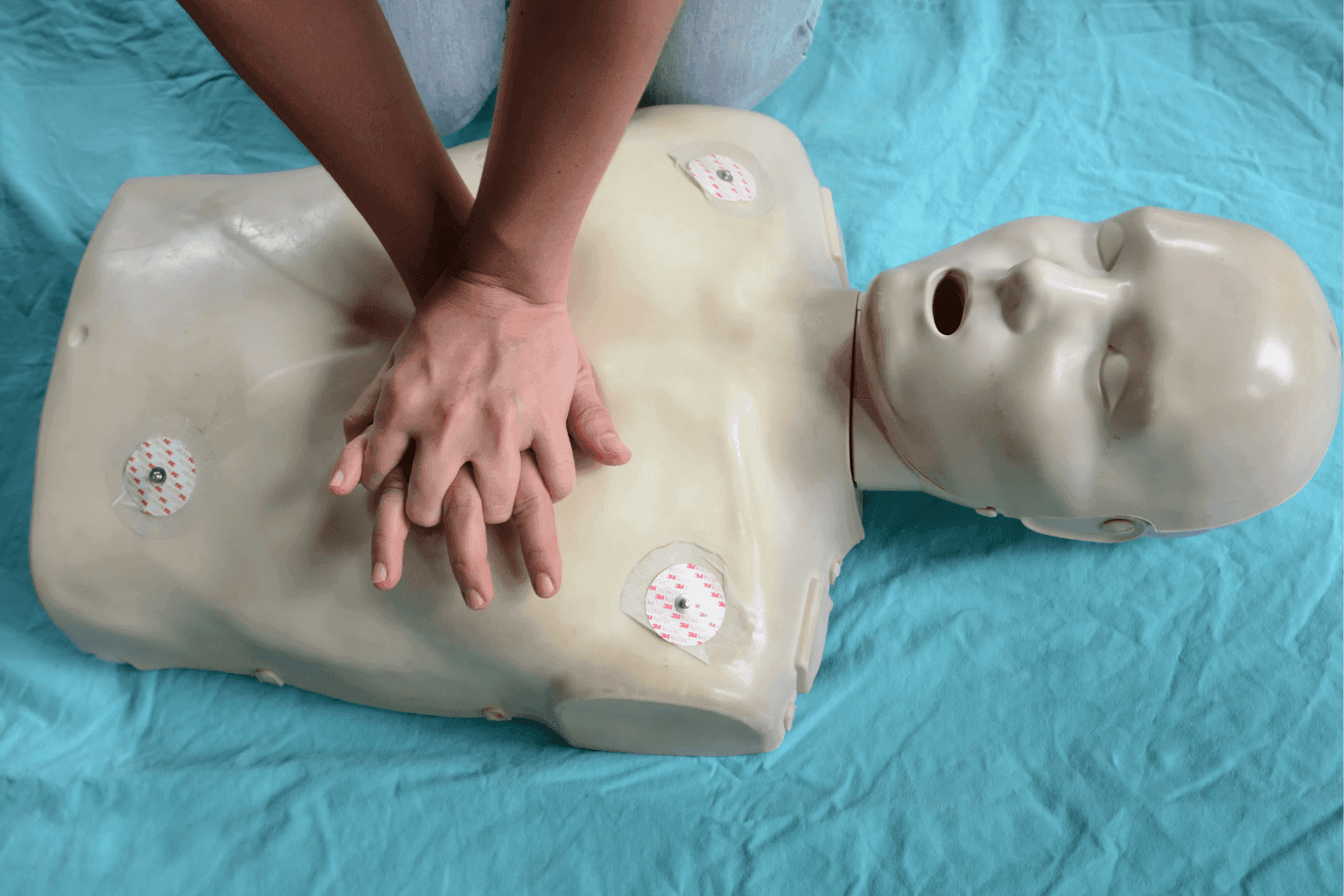 Händer som gör hjärtlungräddning på HLR-docka